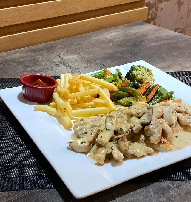 Chicken in cream sauce with fries and vegetables